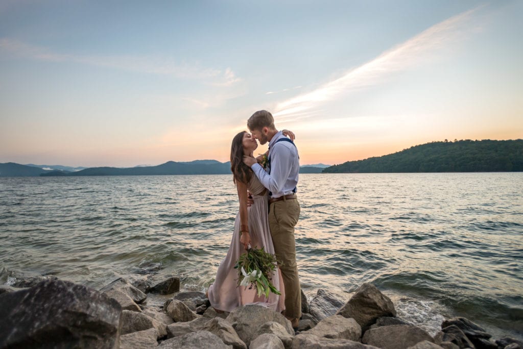 An couple kissing on the rocky shoreline before a lakeside elopoement ceremony in South Carolina