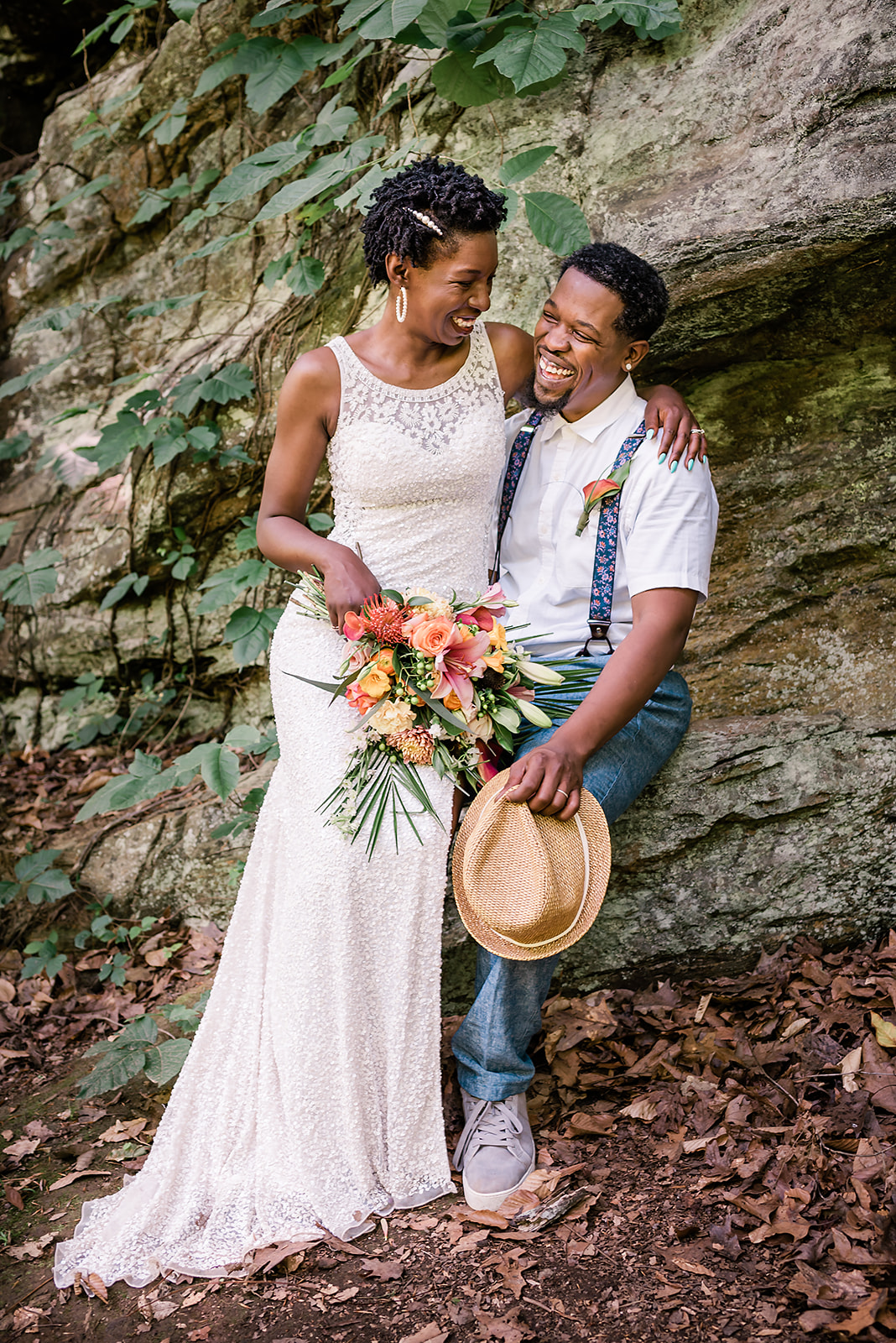 Bride sits on groom's lap on a big rock formation for adventure elopement portraits.