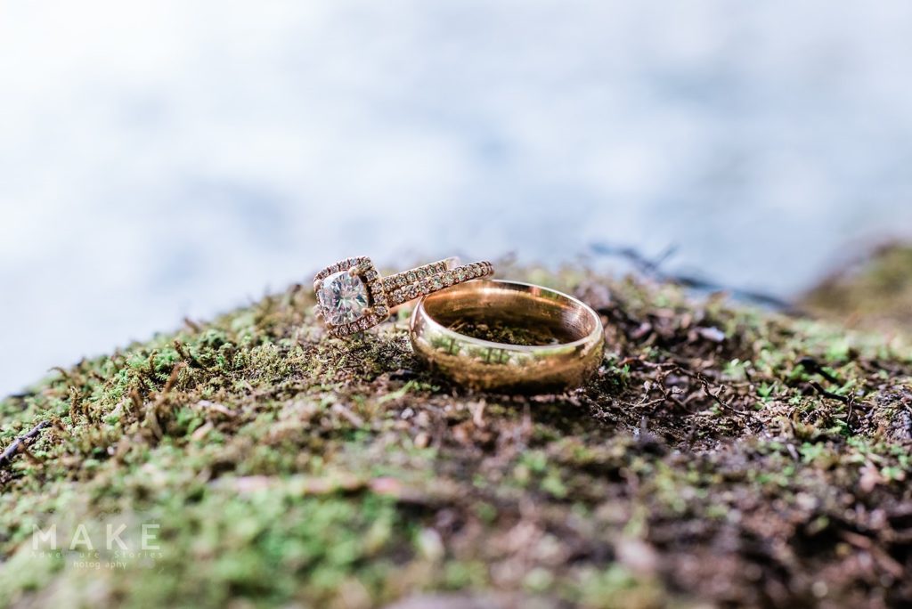 Close up on couple's wedding rings perched on a mossy rock at their courthouse wedding alternative ceremony out in the woods. 