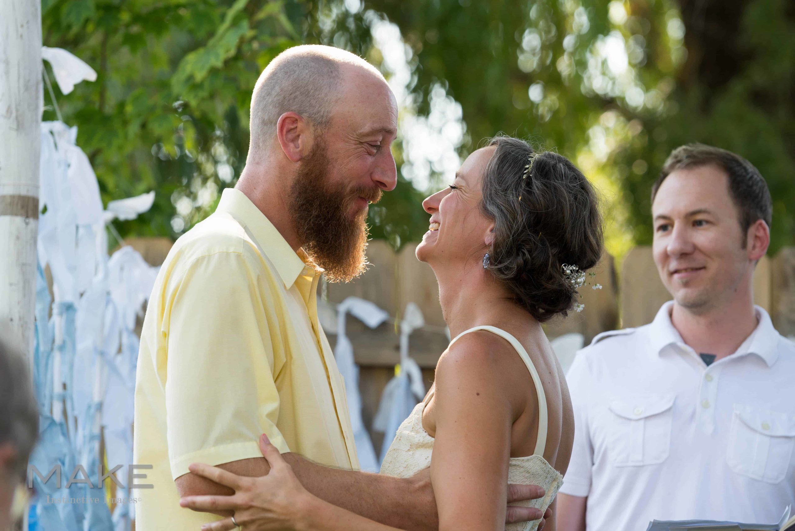 during a backyard wedding a couple faces one another, smiling.