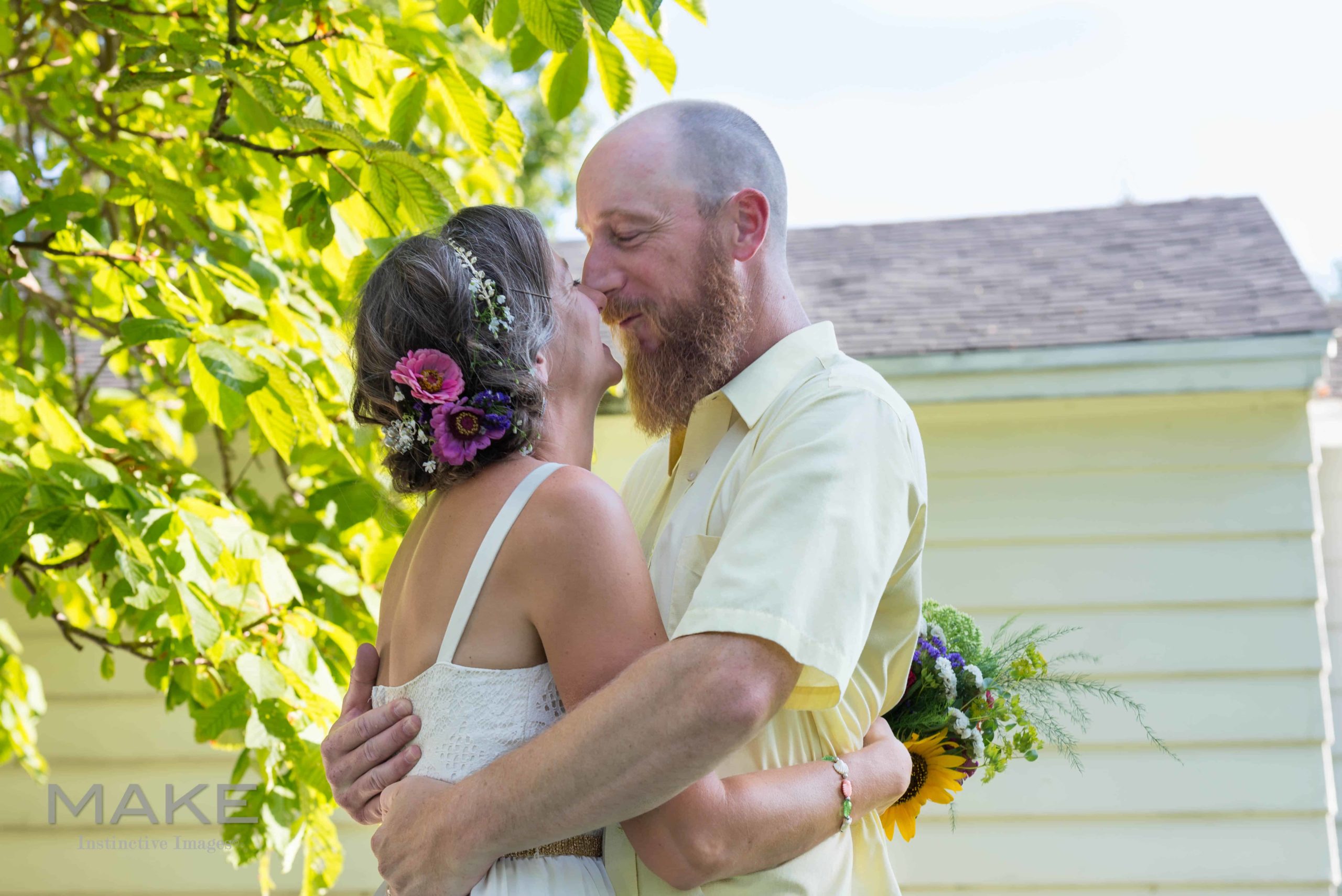 In this backyard minimony wedding type, the couple stands nose to nose for a portrait, hugging and smiling.