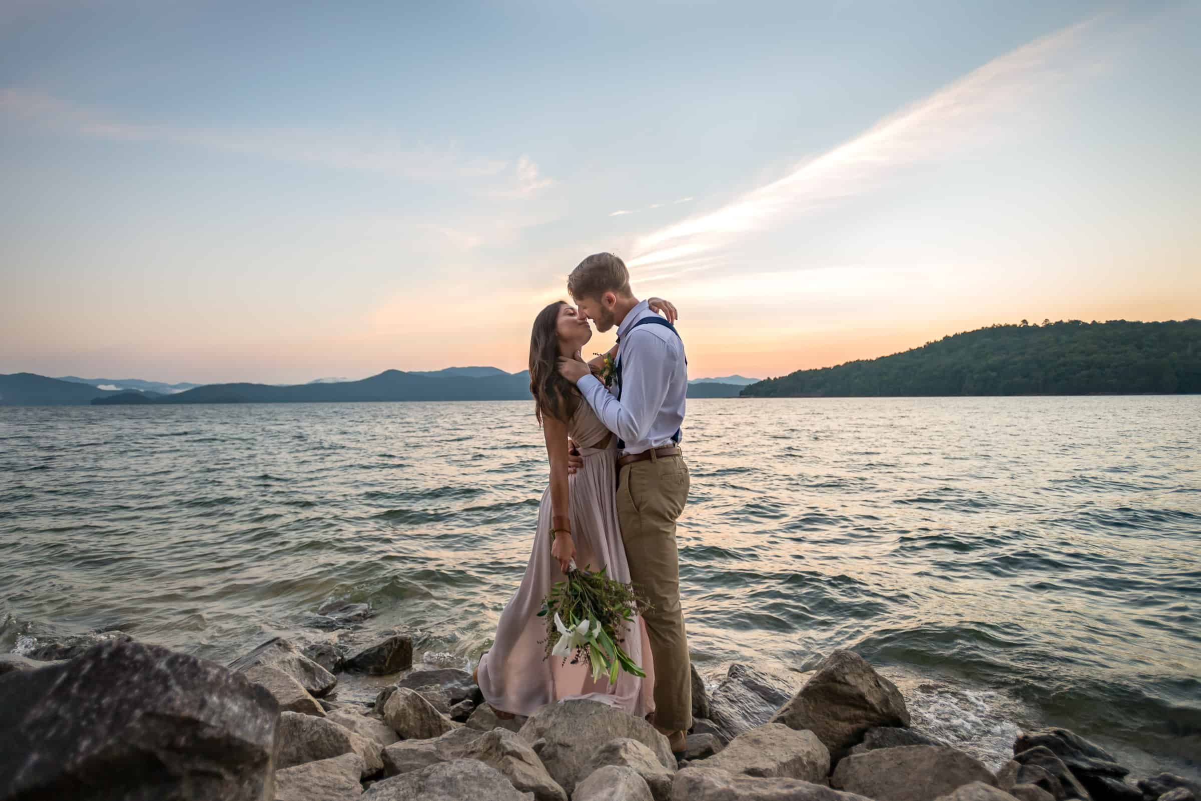 couple leans in for a kiss on the rocky shores at their elopement.