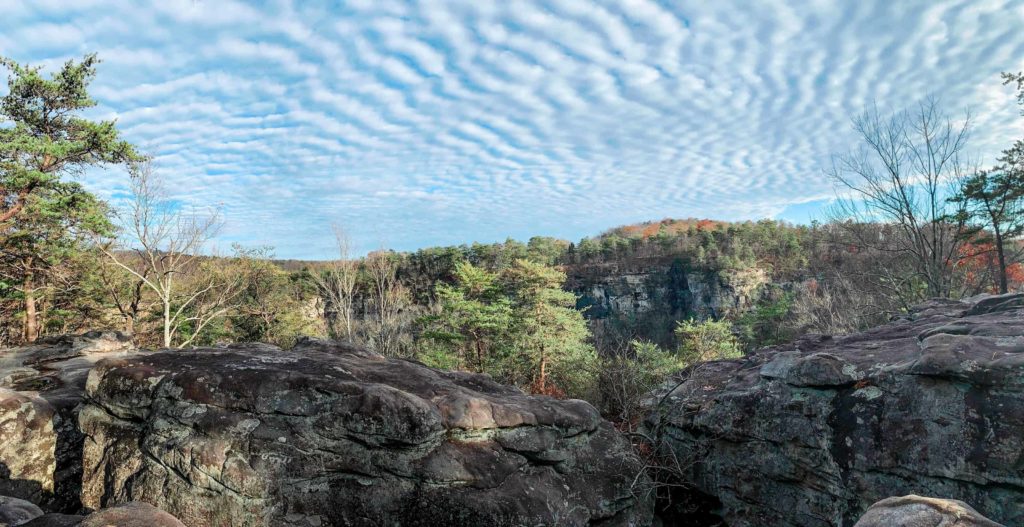 This is an image of Cloud Canyon in Georgia. In this image you can see the mountainous rocks and trees with beautiful cloudy sky.