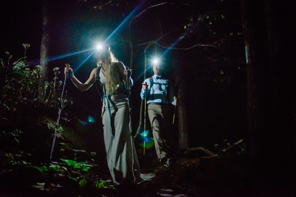 This is a picture of a couple after they shared their vows. For their adventure elopement they went hiking on the Appalachian Trail. This image is of the couple hiking down the trail in the dark with headlamps. 