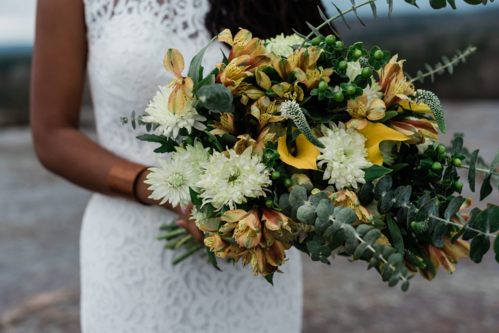 This picture is of a wedding bouquet of yellow, green, and white flowers.