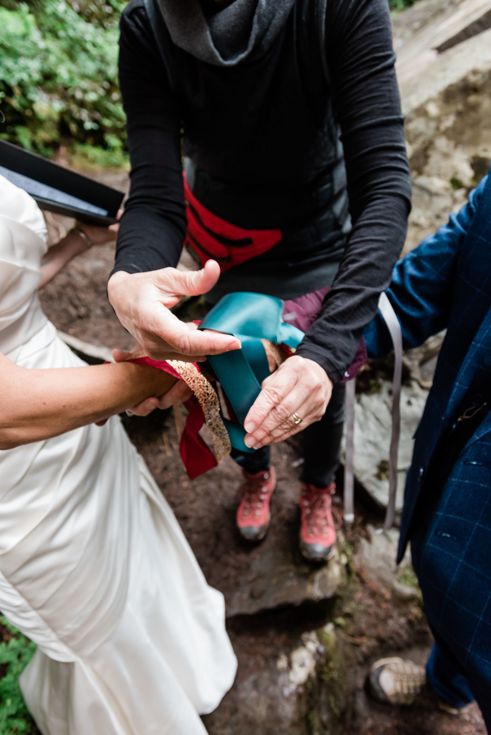 Elopement ceremonies can include lots of ideas. This one had a hand-fasting knotting ceremony with a teal ribbon as seen in this image.