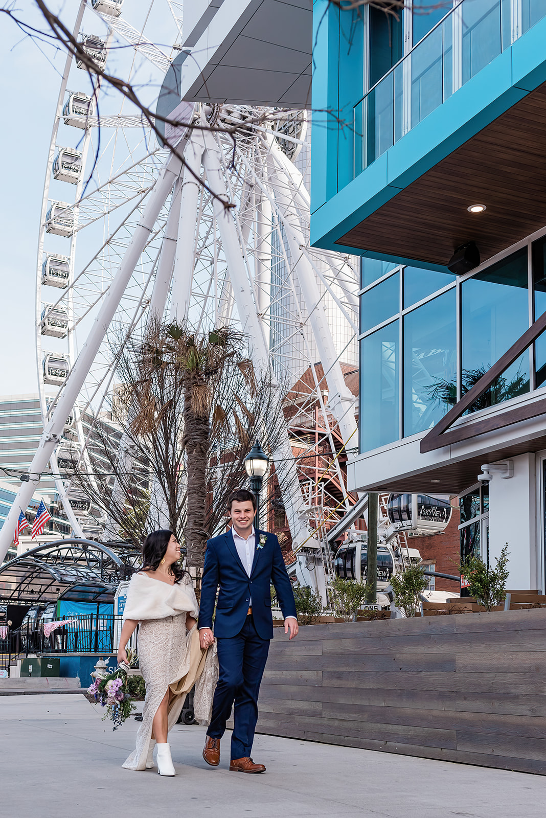 This is a picture of a Ferris wheel taken during an urban elopement. The bride and groom are standing in front of it.