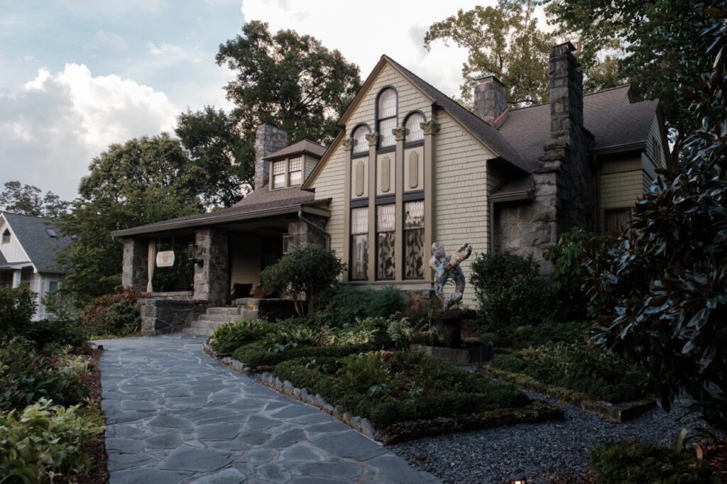 View of the front of Stonehurst Place a beautiful flagstone walkway leading to a historic home with a large wrap-around front porch and green gardens set the stage for a beautiful elopement location in Atlanta