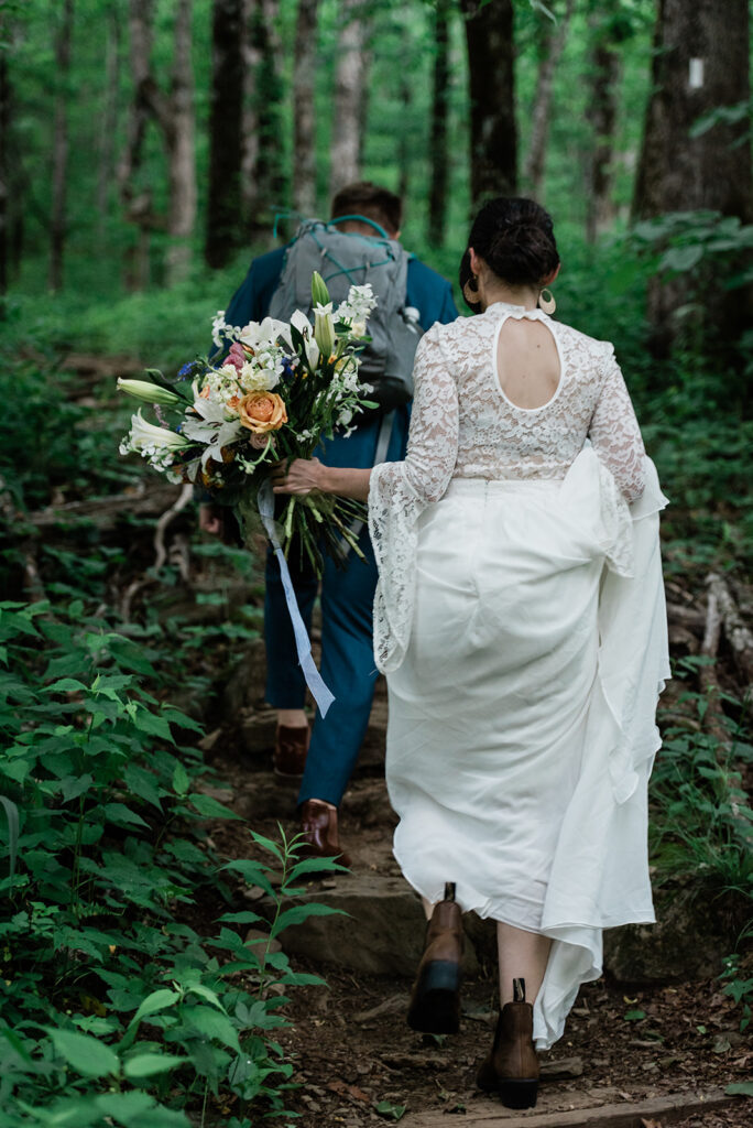 This is a picture of a bride and groom hiking in their wedding attire.