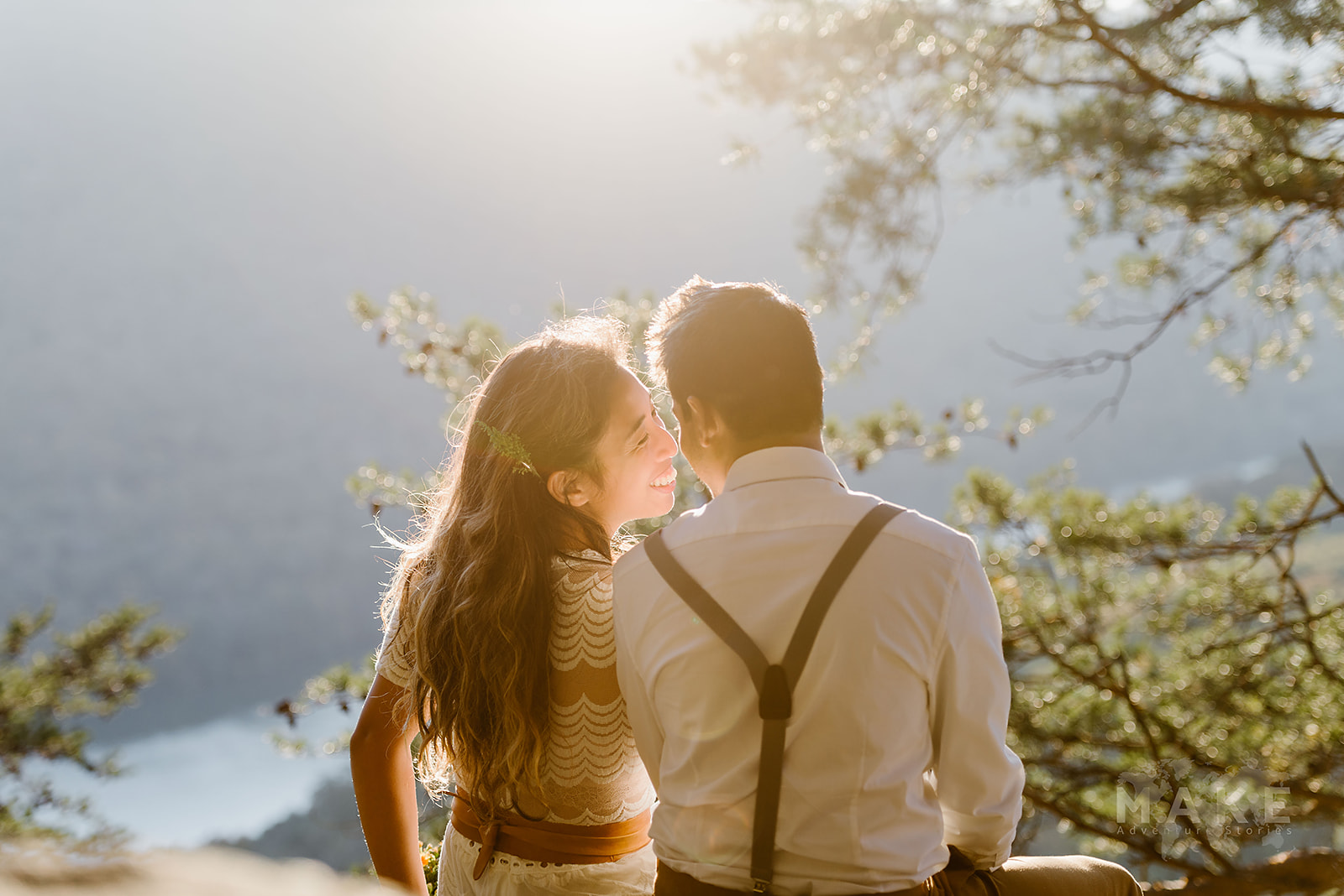 This is a picture of a bride and groom sitting together in the sunshine on the edge of a cliff during their tennessee elopement.