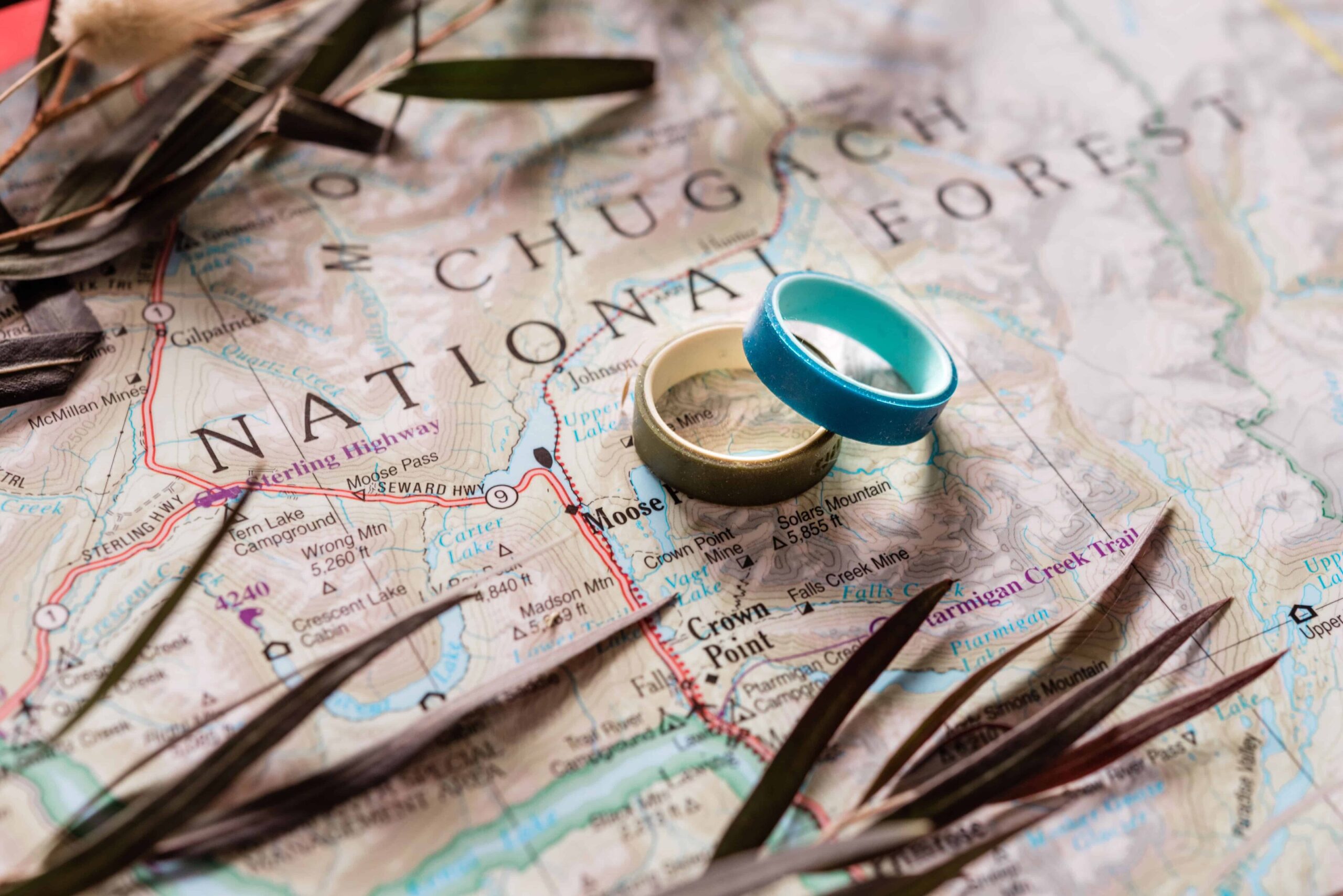 a map of alaska with two silicone rings overlaid on top of the map page, that came from working with an adventure elopement planning package as part of the couple's elopement