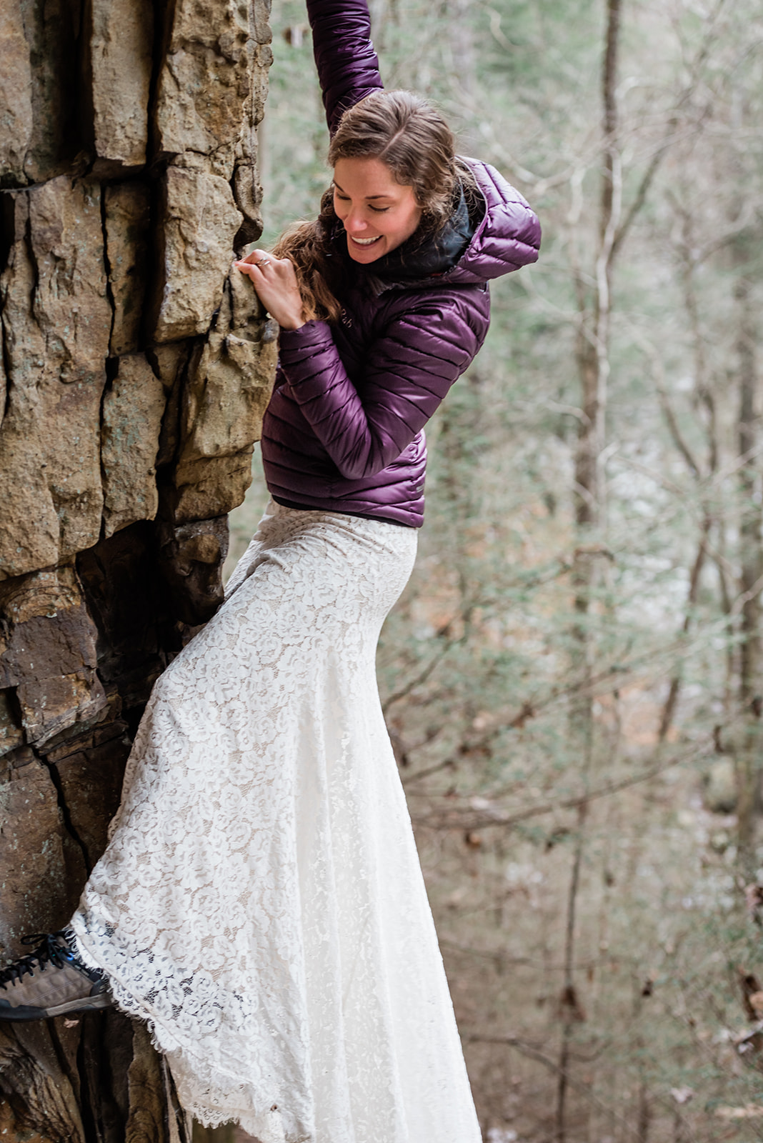 This is a picture of a bride in her wedding dress rock climbing.